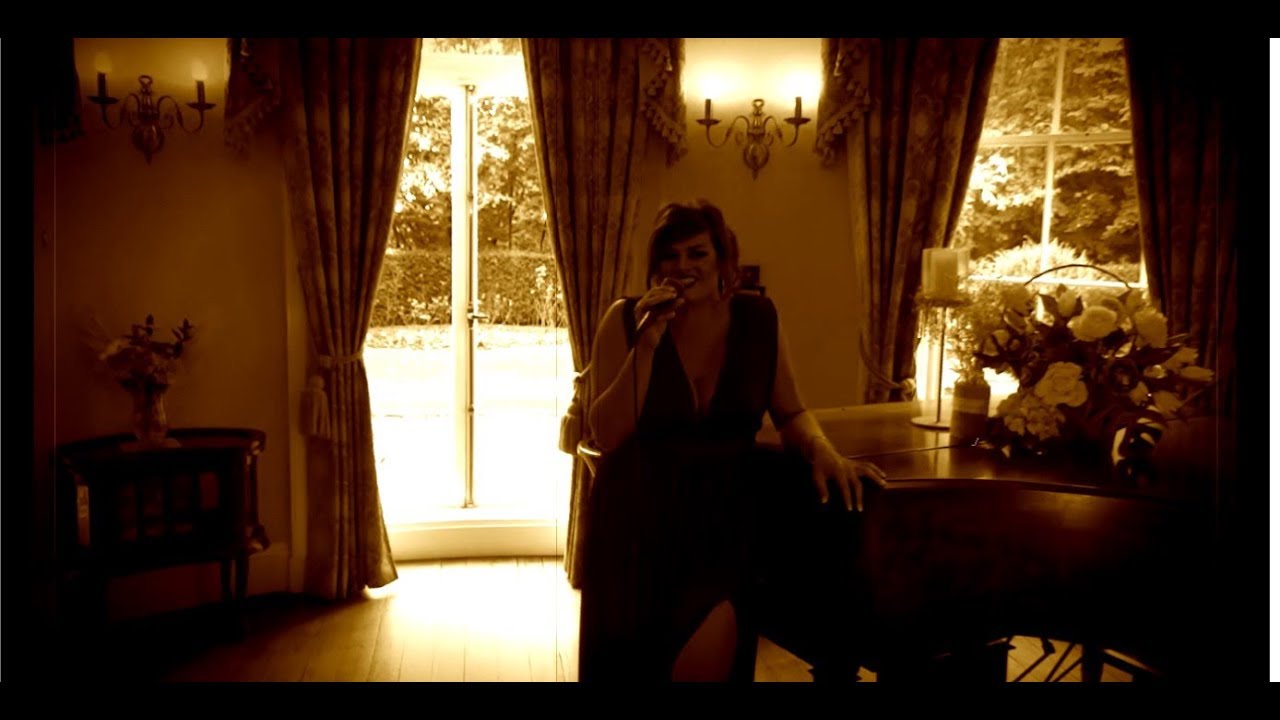 Sadie-Beth Holder singing beside a grand piano